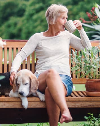 Older woman drinking coffee on bench